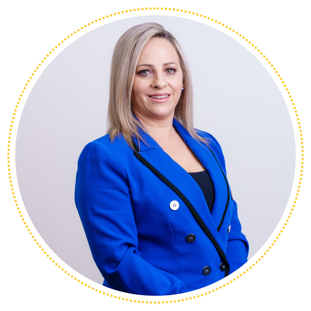 Kelly, a white lady with blonde hair, wearing a light black shirt with a bright blue suit jacket, smiling at the camera