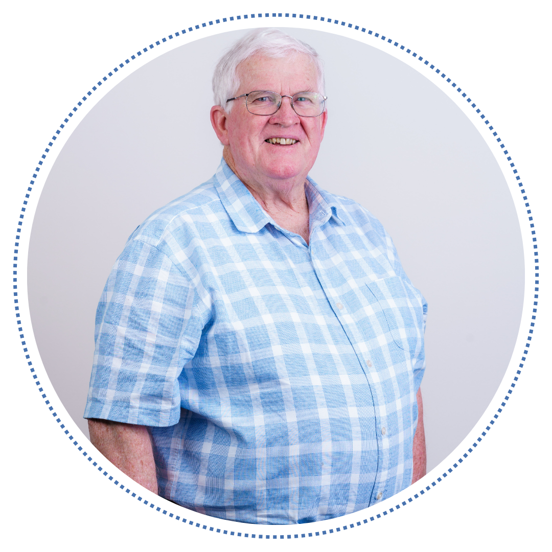 Stewart, a white man with grey hair and thin glasses, wearing a light blue checkered button up shirt, smiling at the camera