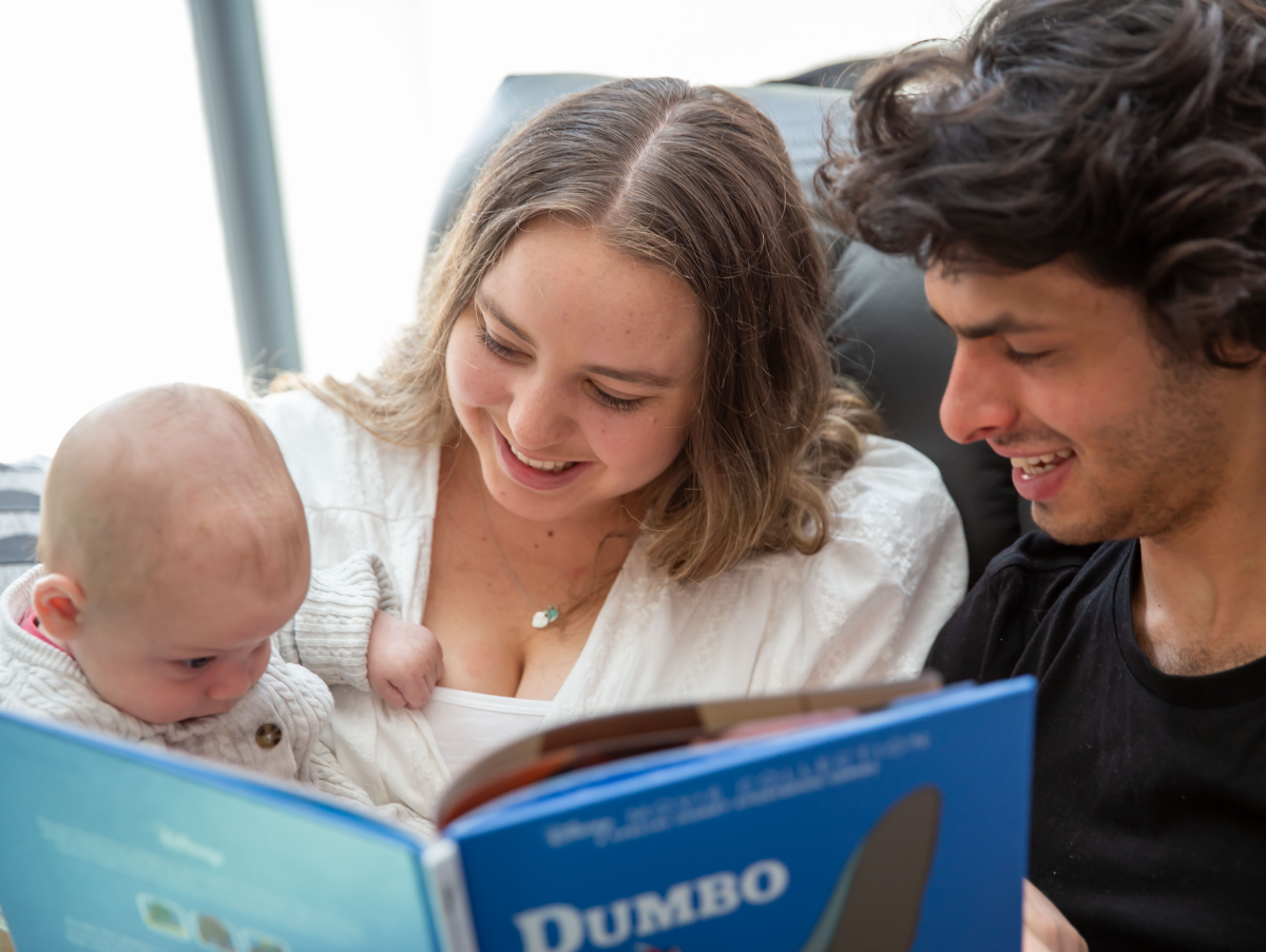 A mum and dad are reading their new born baby a book in the Ronald McDonald Family Room at Gosford