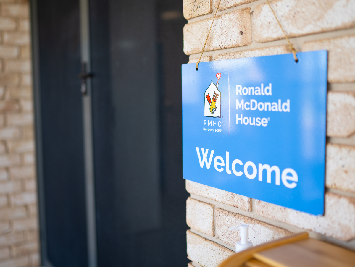 A blue sign handing off of a brick wall at Ronald McDonald House Tamworth. The sign reads "Welcome"